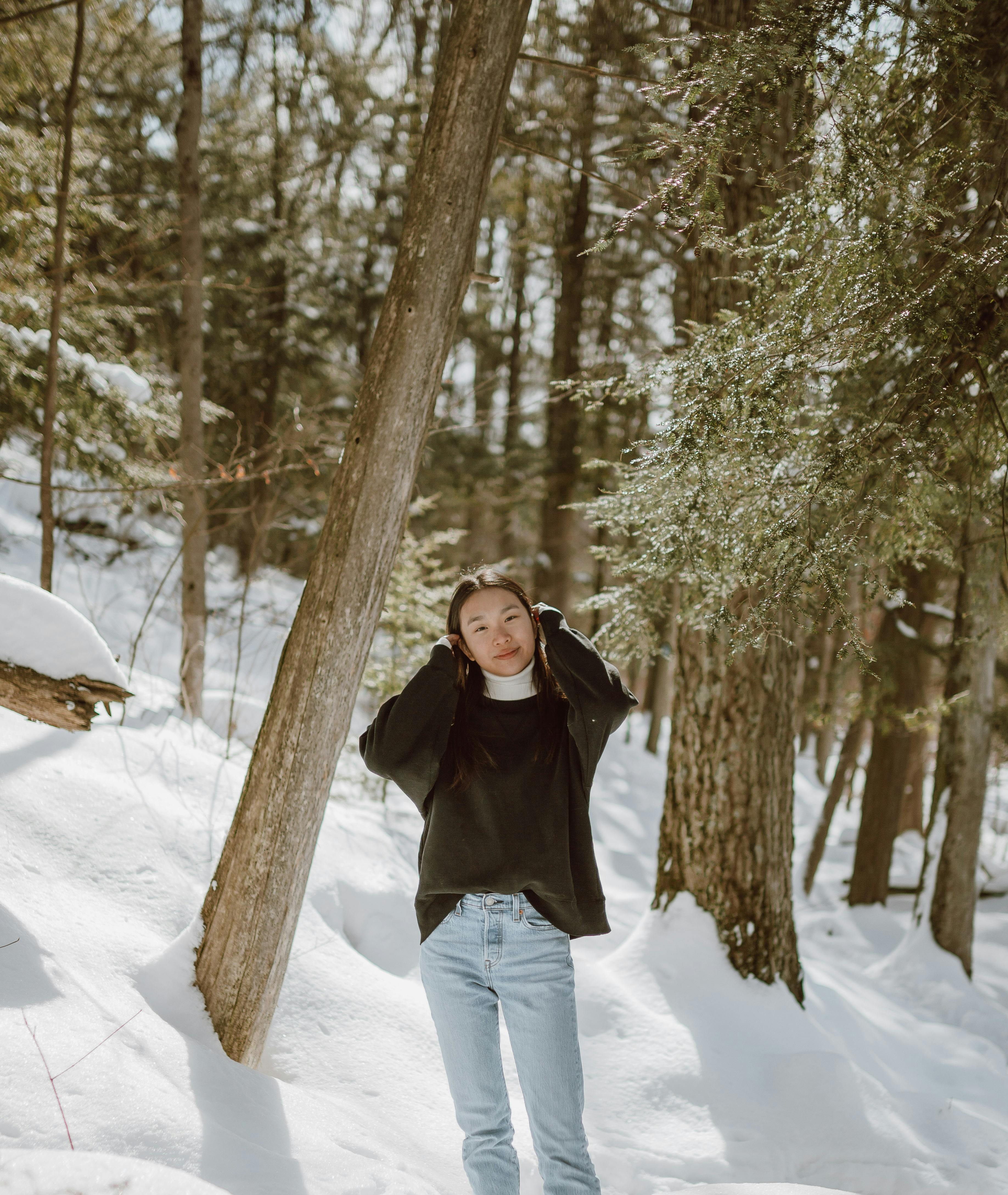 Smiling female walking on road among snowy forest · Free Stock Photo