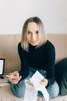Young woman in black turtleneck managing finances with receipts and calculator at home.