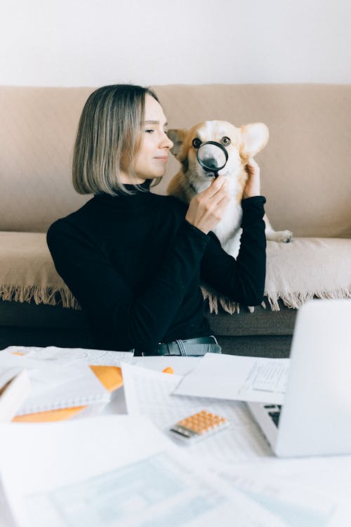 Woman in Black Long Sleeve Shirt Holding a Magnifying Glass on Dog's Nose