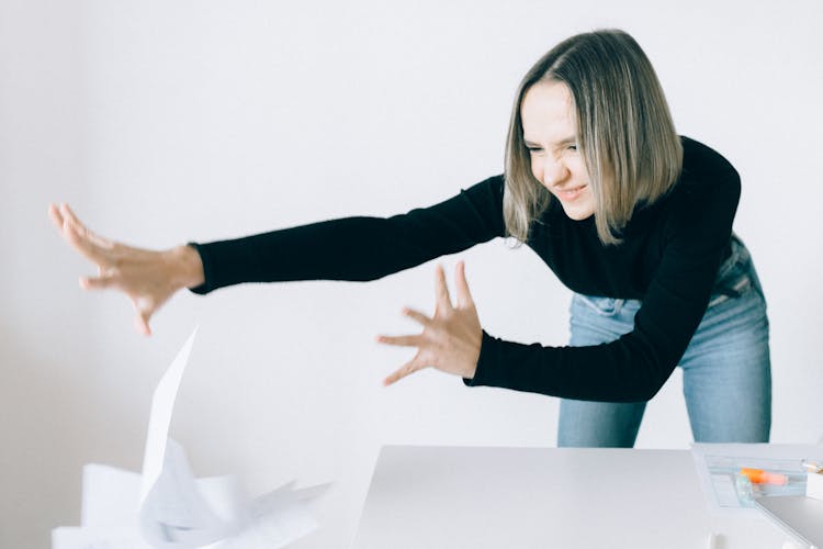 A Woman In Black Long Sleeves Throwing Papers From The Table