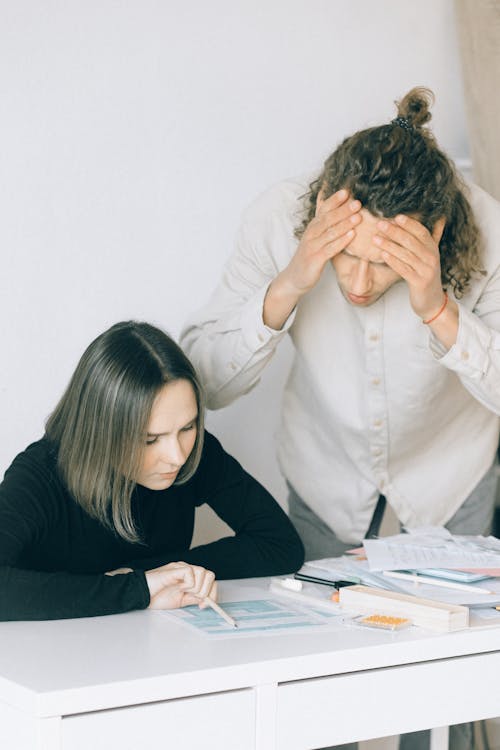 A Man and Woman Arguing while Looking at the Papers on the Table