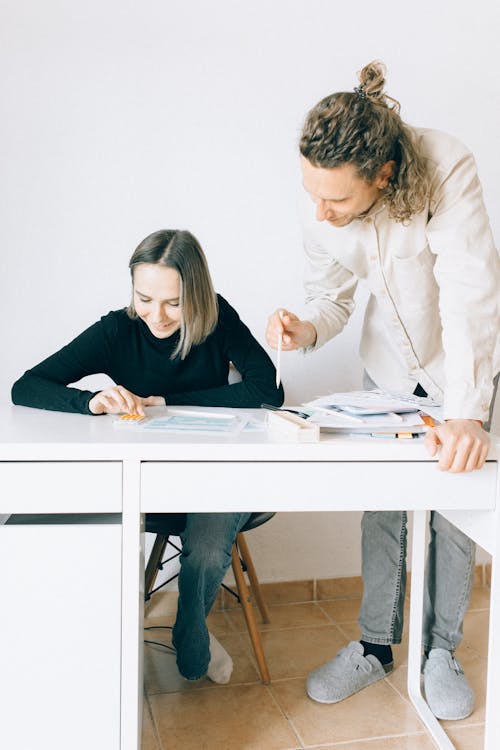 A Man and Woman Having Conversation while Looking at the Papers on the Table