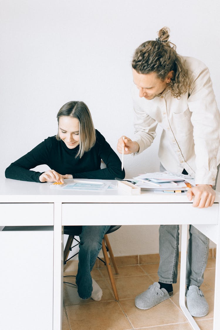 A Man And Woman Having Conversation While Looking At The Papers On The Table