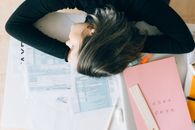 Woman in Blue Long Sleeve Shirt Lying on White Printer Paper