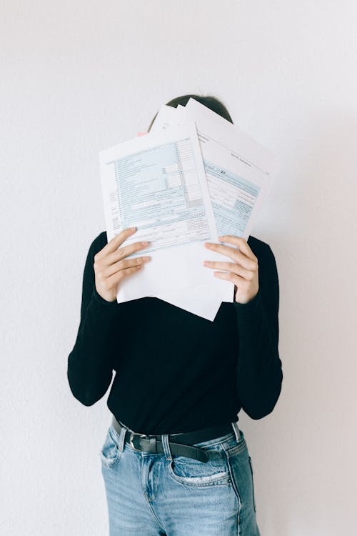 Woman Covering Her Face With Tax Forms
