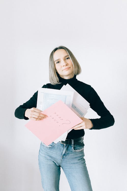 Free Woman in Black Turtleneck Shirt and Denim Pants Holding Paperworks Stock Photo