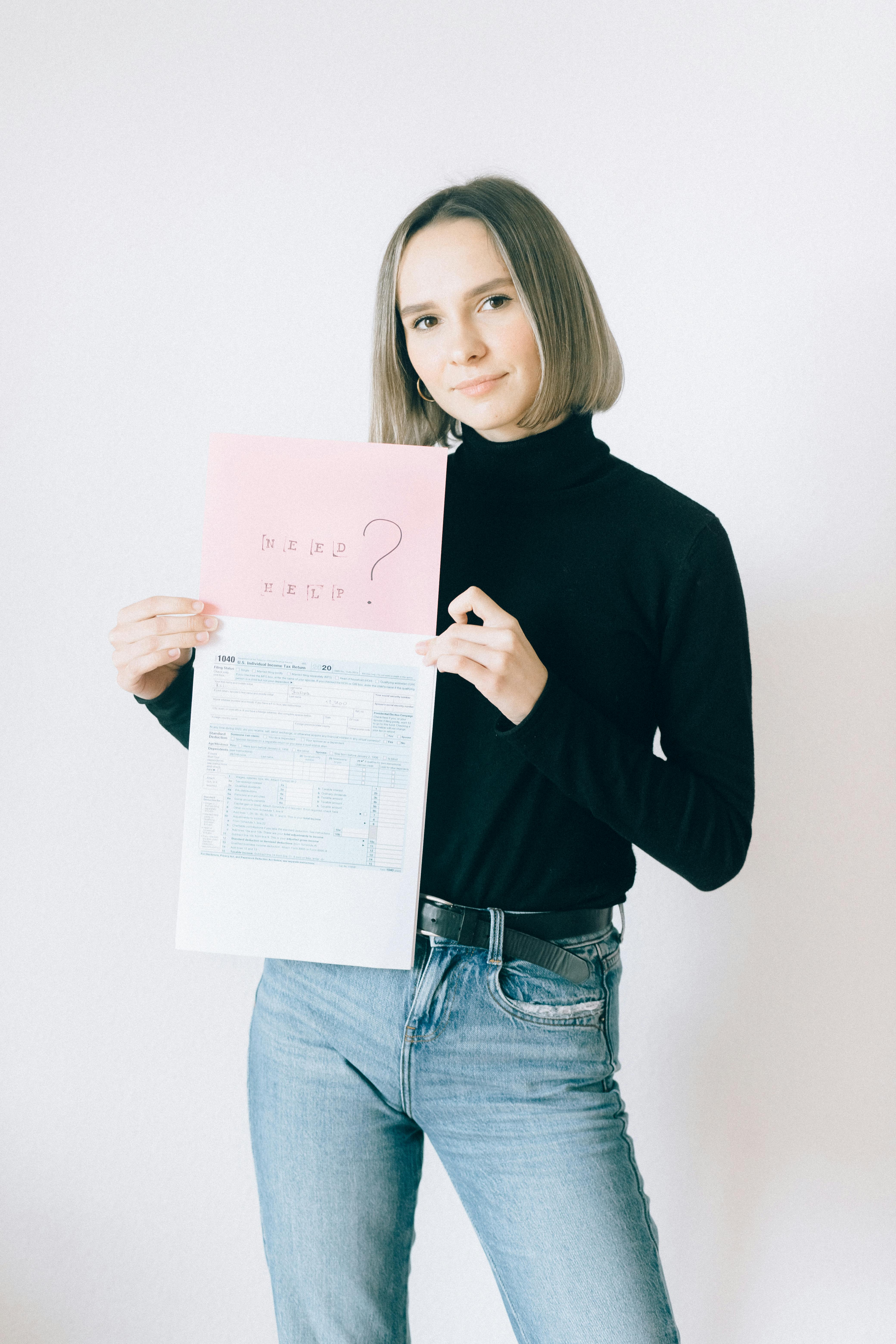 woman in black long sleeve turtleneck shirt holding tax forms and offering help