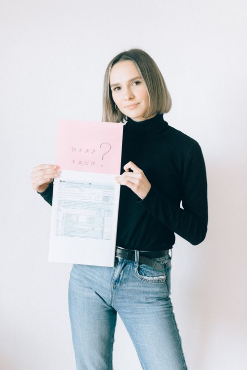 Free Young woman with paperwork holding tax forms and question sheet. Stock Photo