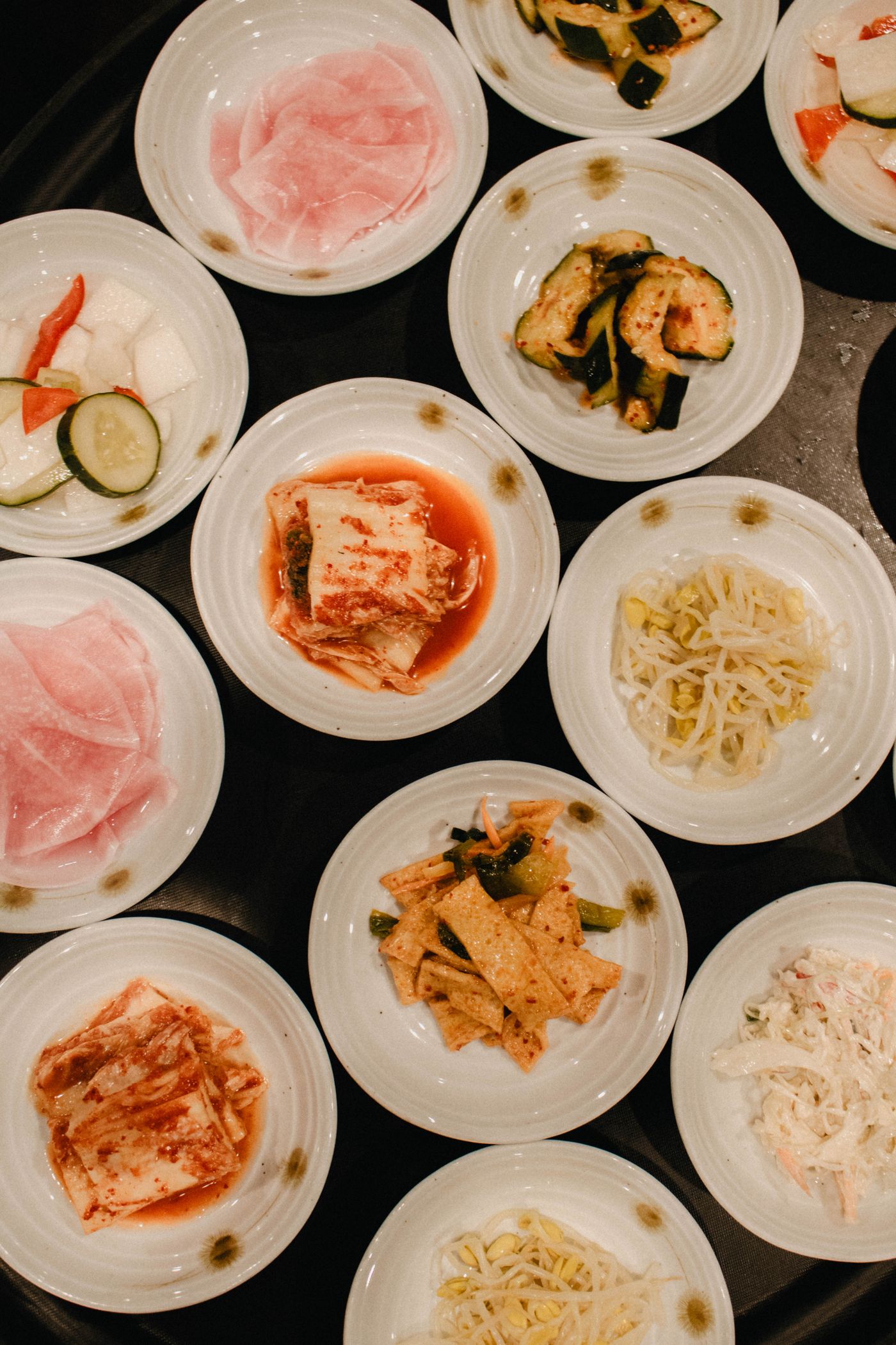 Many small white dishes of Korean banchan side dishes