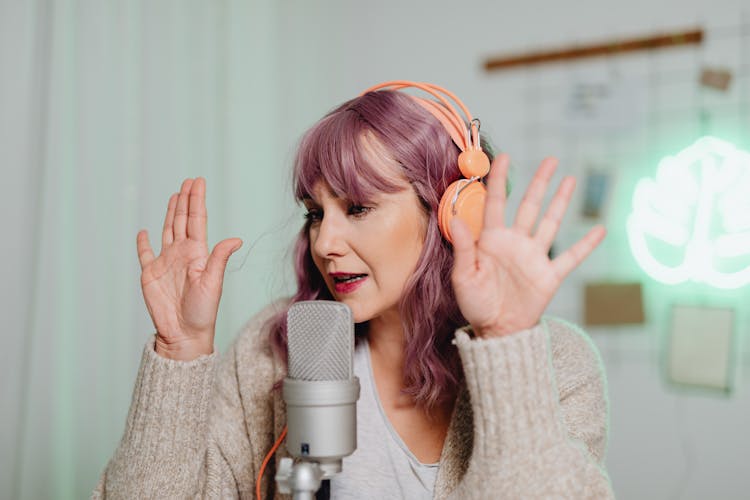 A Woman Talking On A Microphone While Wearing A Headphone