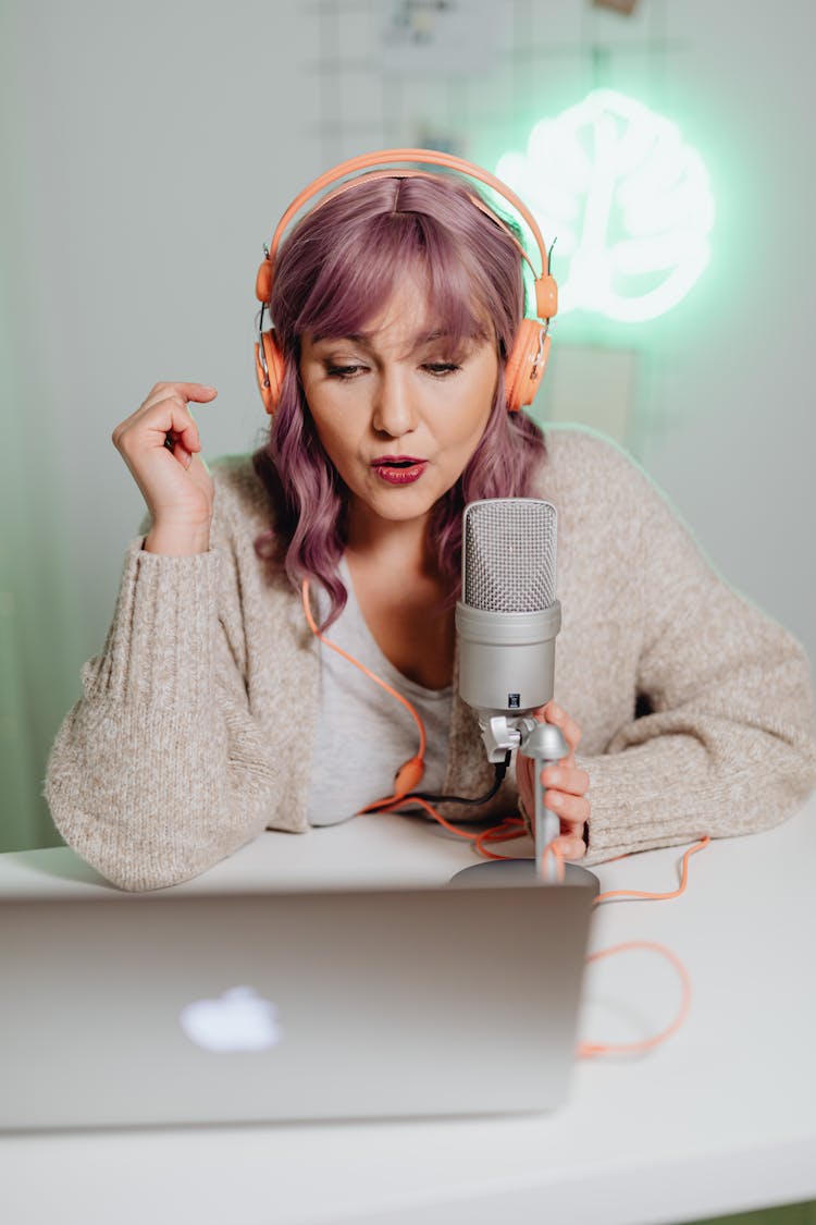 A Woman Talking On A Microphone While Wearing A Headphone