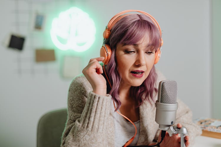 A Woman Talking On A Microphone While Wearing A Headphone