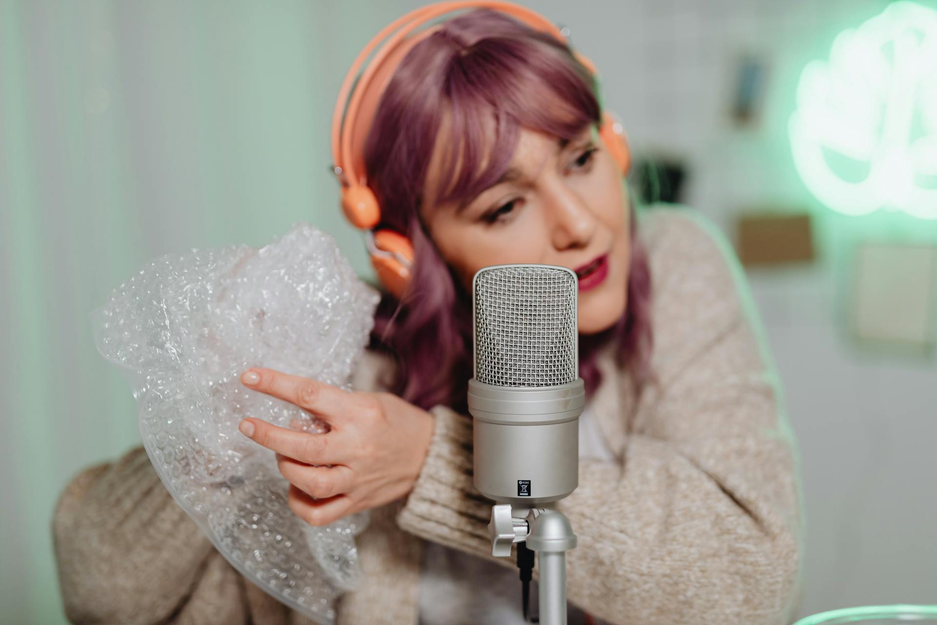 Woman in Knit Sweater Wearing Headphones Holding Bubble Wrap