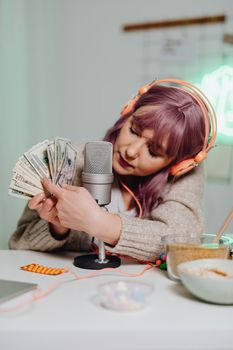 Female podcaster with cash and microphone in cozy studio setting, showcasing modern media lifestyle.