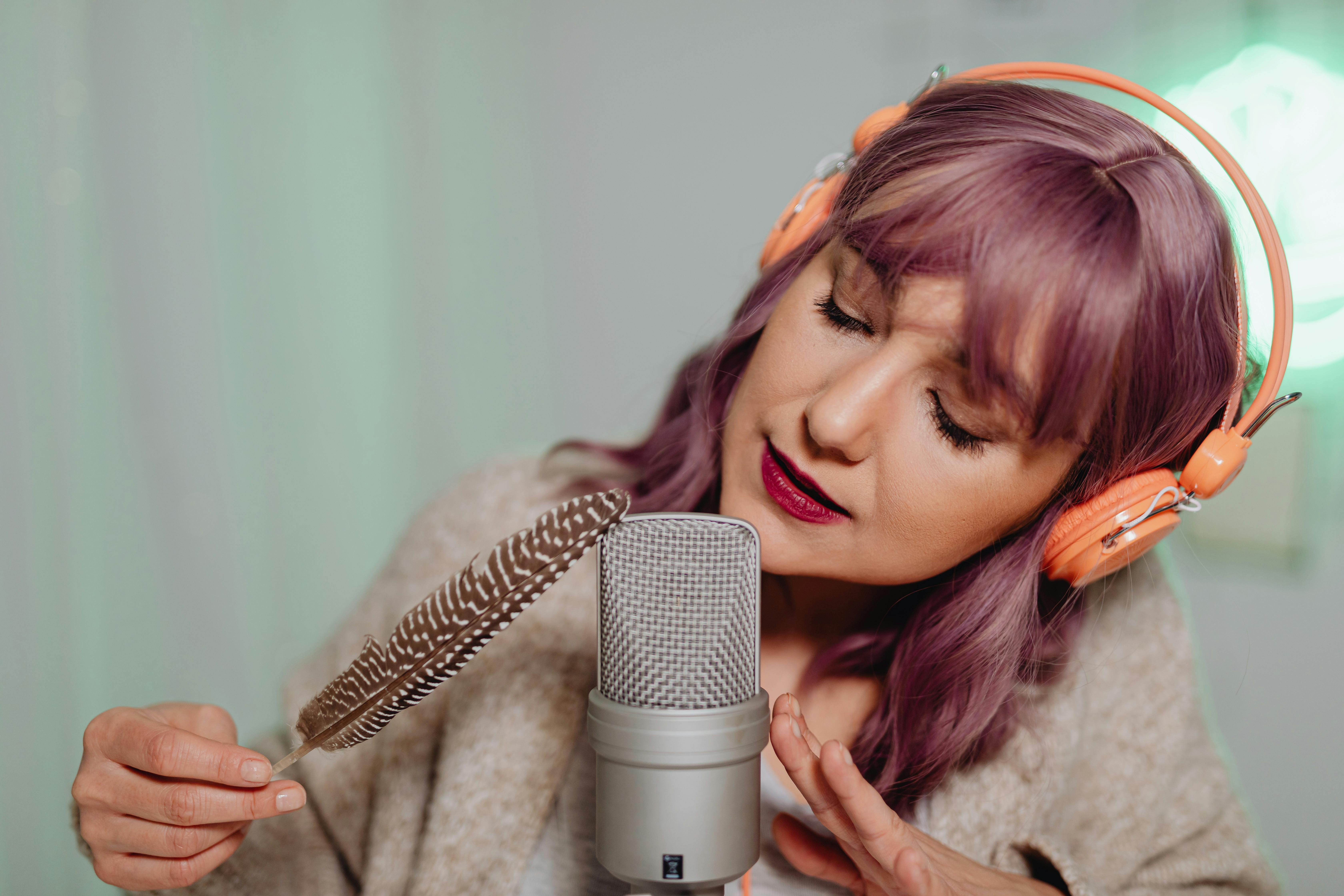 a woman holding a feather close to a microphone