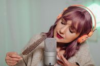 A Woman Holding a Feather Close to a Microphone