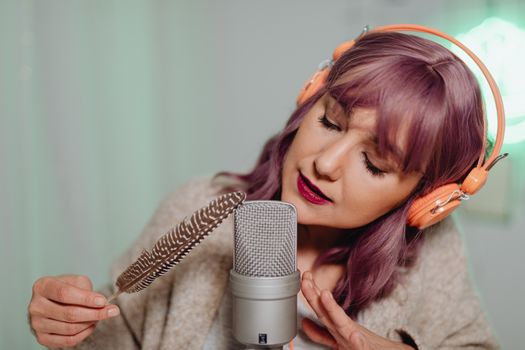A Woman Holding a Feather Close to a Microphone