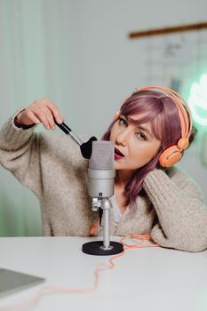 Woman in cozy setup using brush and microphone for ASMR recording at home.