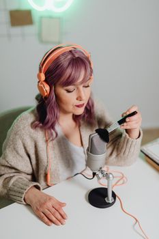A woman recording ASMR content using a microphone and brush indoors.