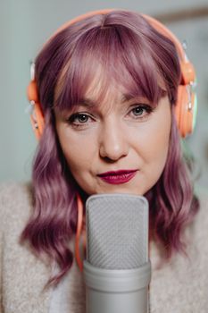 Close-up of a woman recording audio indoors with a headset and microphone.