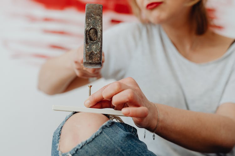 A Person Hammering A Nail