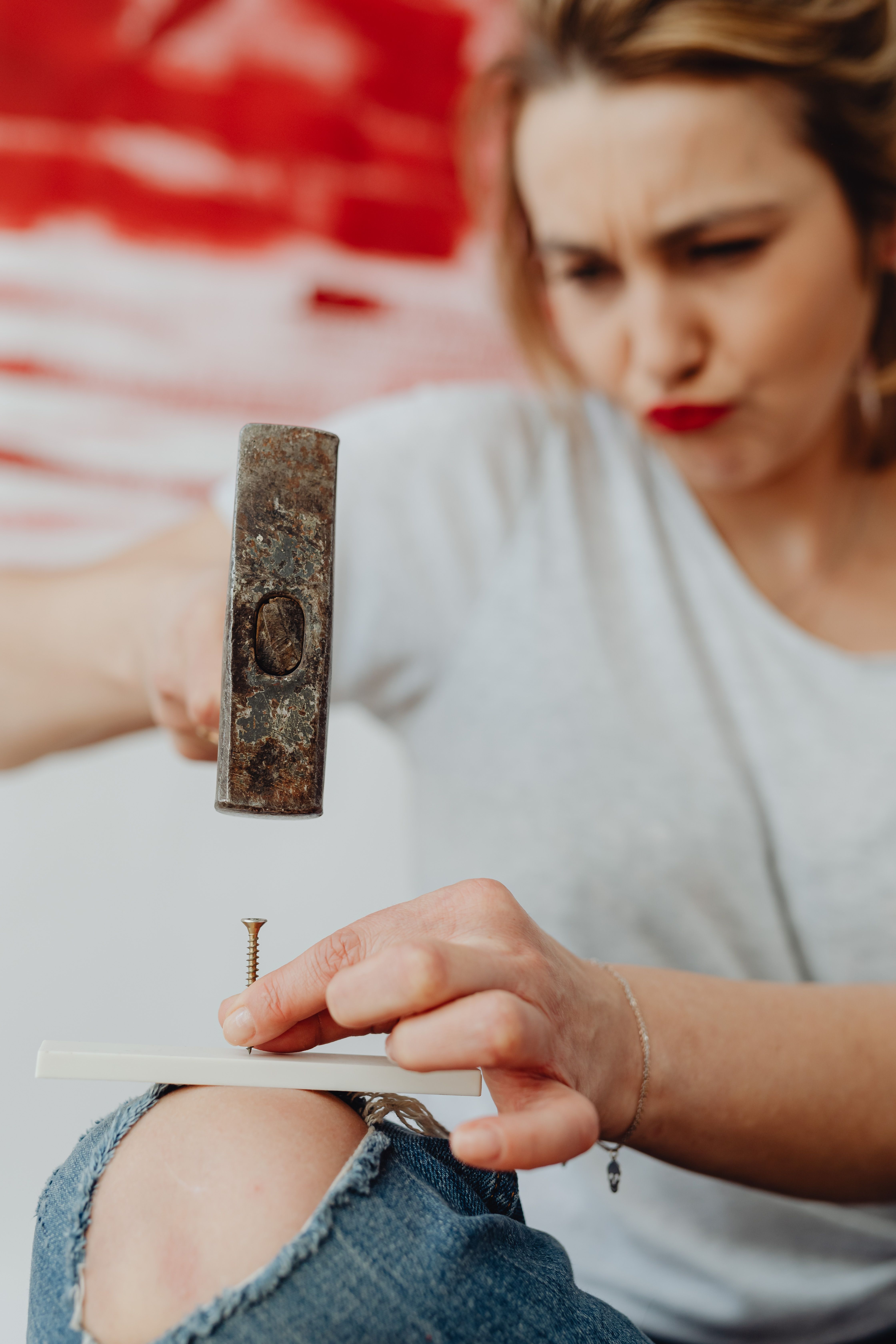 Focused woman hammering a nail into wood - DIY home improvement concept.