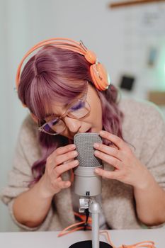 Woman wearing headphones recording ASMR content indoors with a microphone.