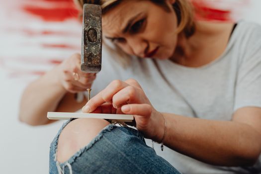 A close-up shot of a woman intensely focused on hammering a screw.