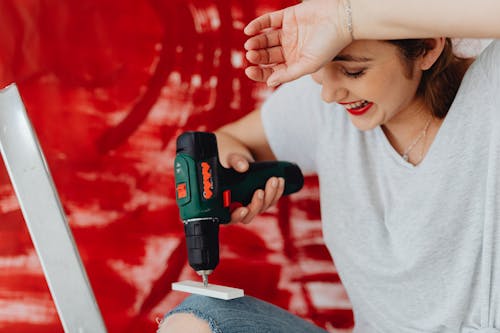 Free A Woman in Gray Shirt Holding a Hand Drill Stock Photo
