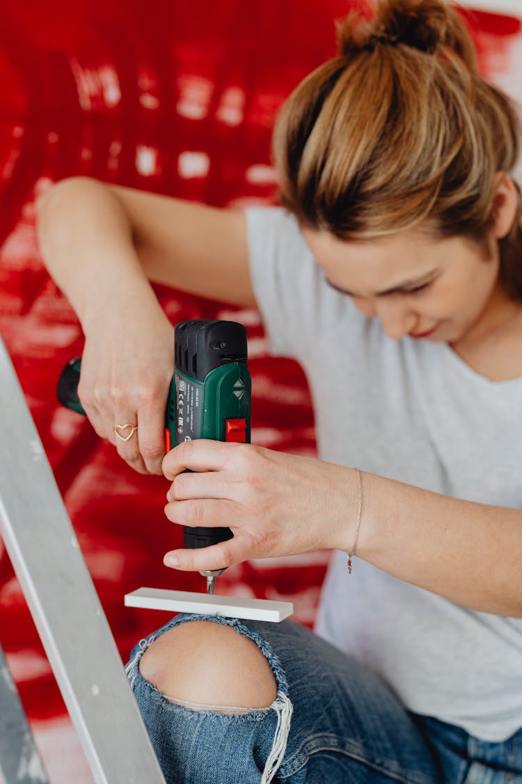 Woman Using A Drill And Red Abstract Painting In Background