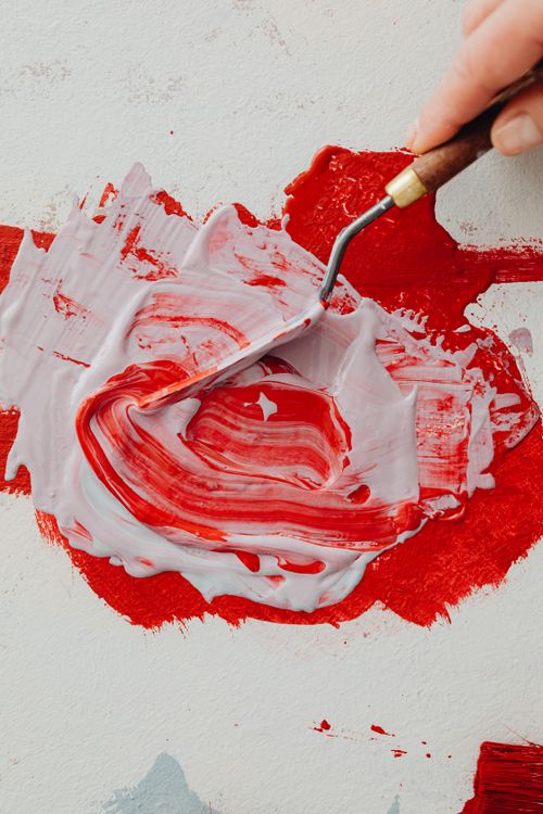 Free Artistic close-up of red and white paint being mixed with a palette knife. Stock Photo