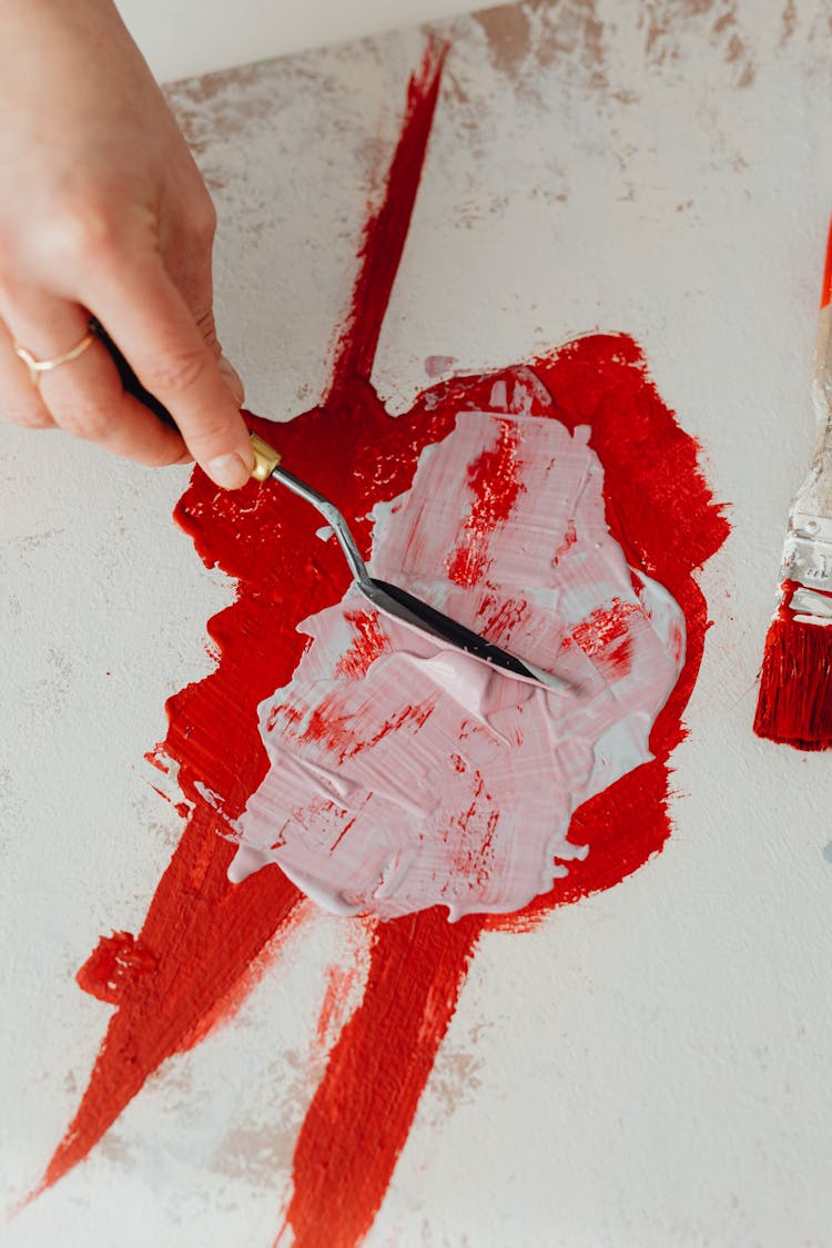 Woman Mixing Red And White Paint With Palette Knife