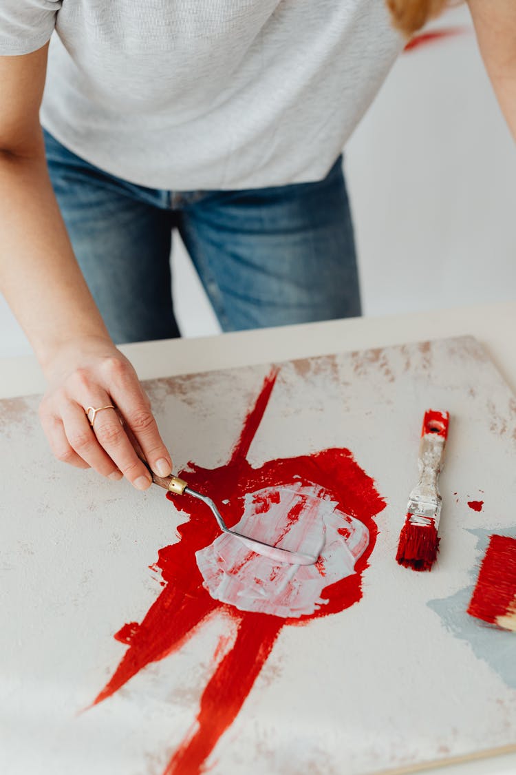 Woman Mixing Red And White Paint Using Palette Knife