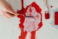 Person Holding Red Paint on White Wall