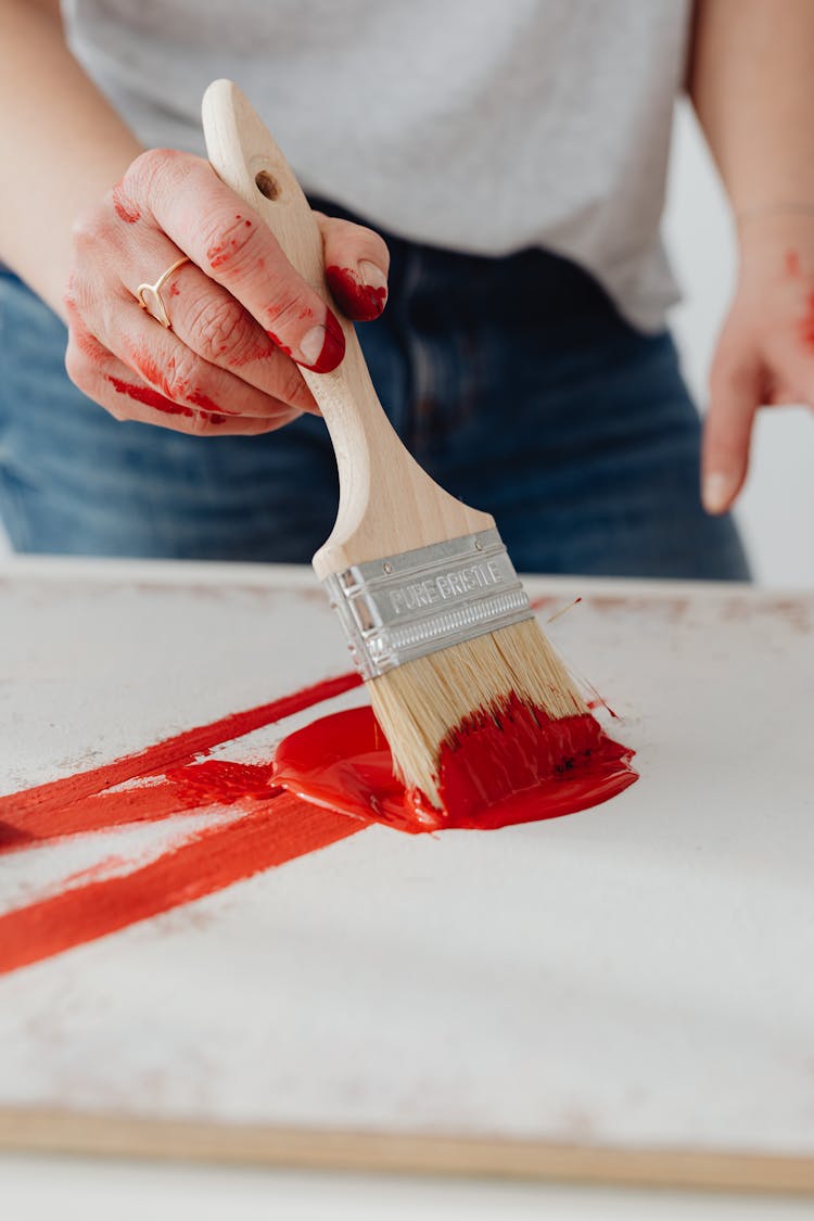 Close-up Of A Woman Painting And Her Hands Dirty From Red Paint