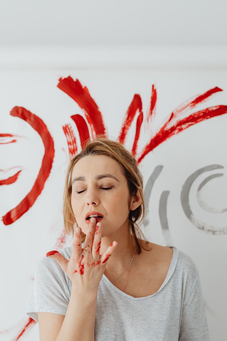 Portrait Of A Painter Touching Her Lips And Red Paint Strokes On A Wall