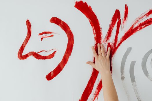 Abstract red hand painting with expressive brushstrokes on canvas wall.