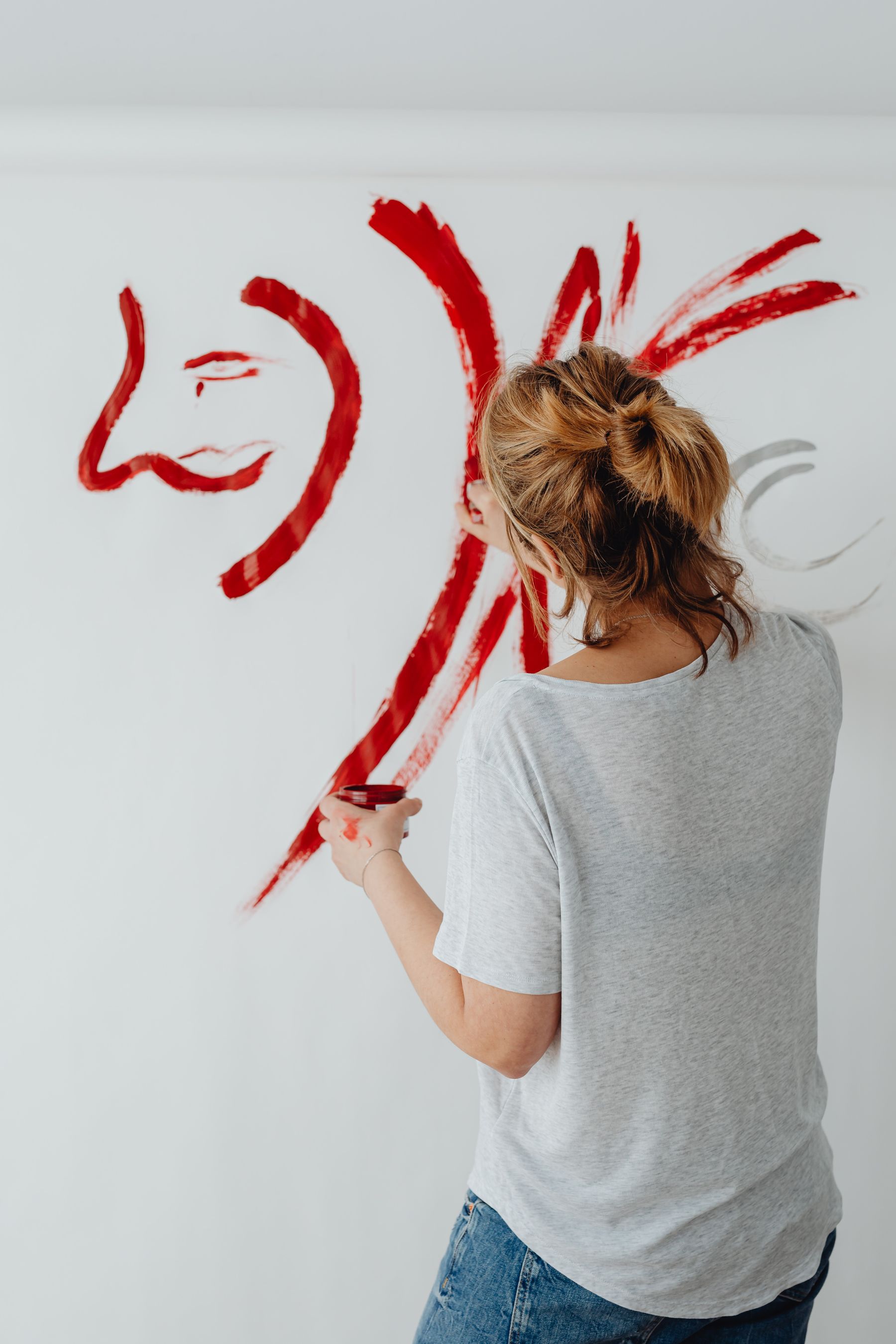 An artist painting a red stroke on a white wall
