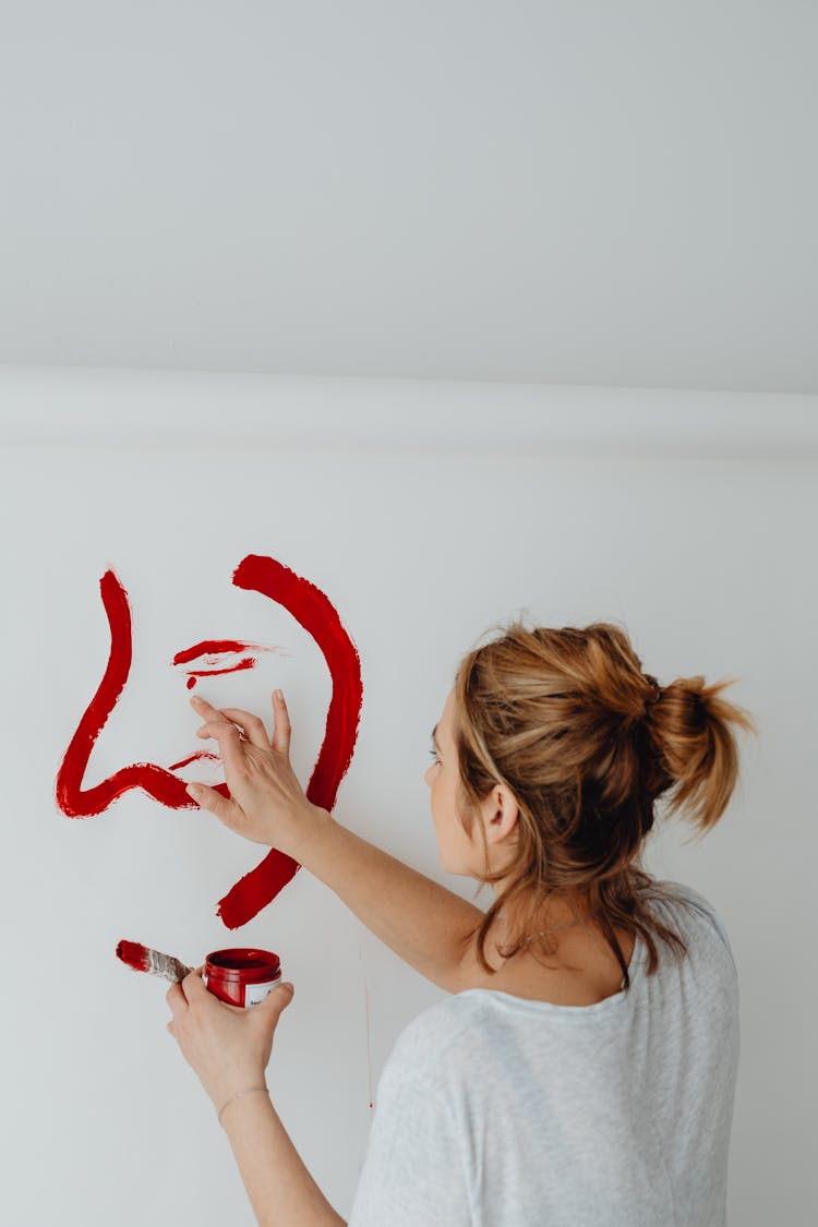 Woman Painting With Red Paint On A White Wall