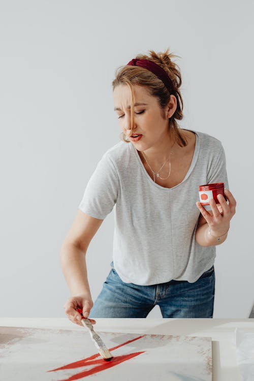 Free Photo of a Woman Painting while Holding a Paint Cointainer Stock Photo