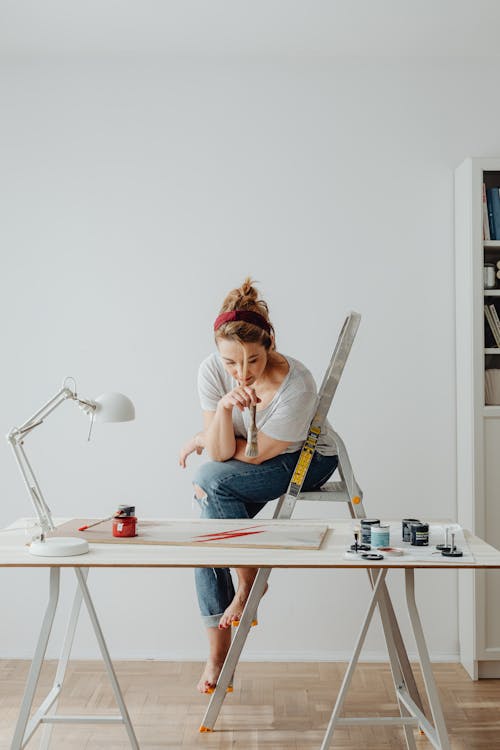 Free Woman Sitting on a Stepladder while Painting Stock Photo