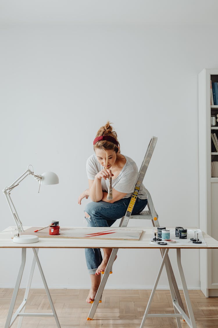 Woman Sitting On A Stepladder While Painting