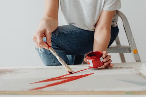 Free Close-up of a woman painting with a brush and vibrant red paint on canvas. Stock Photo