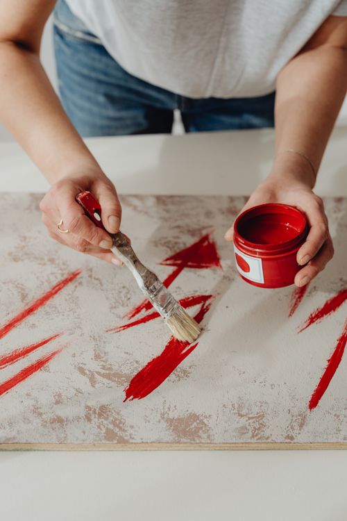 Free Hands painting red strokes on canvas with paintbrush. Creative expression and artistic style. Stock Photo