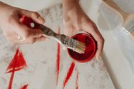 Photo of a Person Getting Paint in a Container