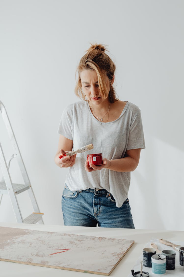 Blonde Woman Painting A Board Using White And Red Paint