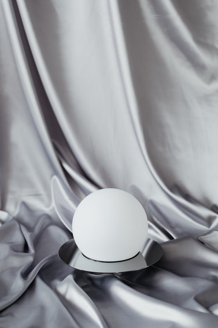 White Ball Against A Silver Fabric