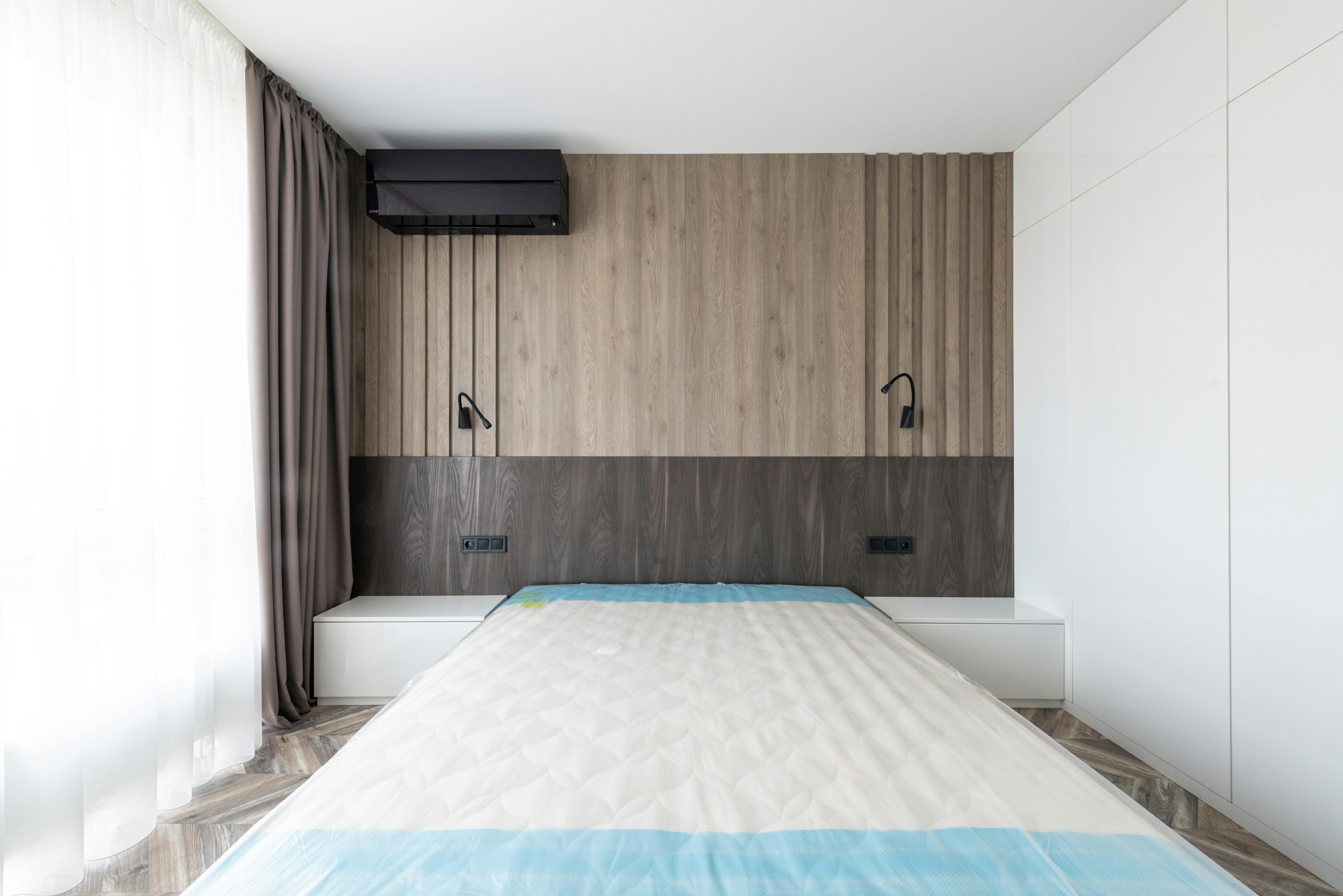 Detail einer paneelartigen Wandverkleidung hinter dem Bett mit sauberer Kante und warmer Holzoptik