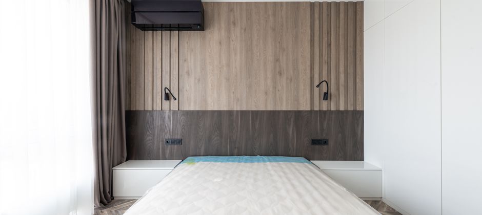 A bedroom with a wooden bed frame and headboard — the joints and seams where bed bugs actually harbour