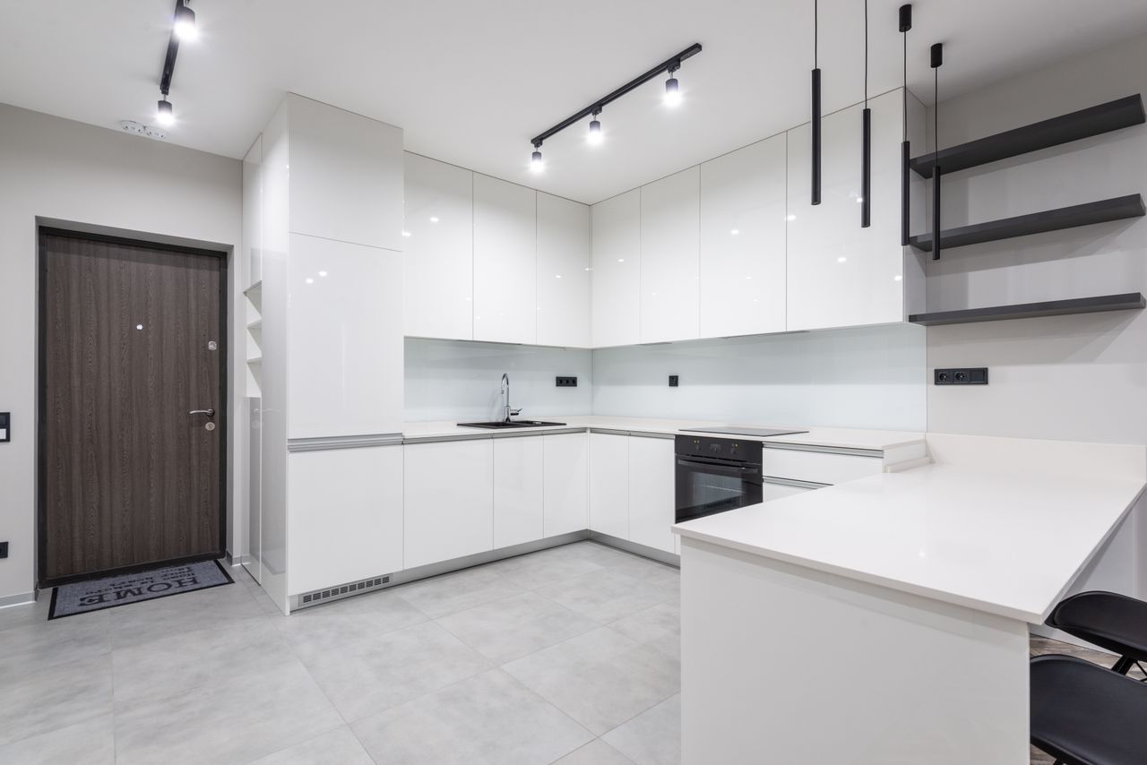 Modern white kitchen with black open wall shelves and track lighting